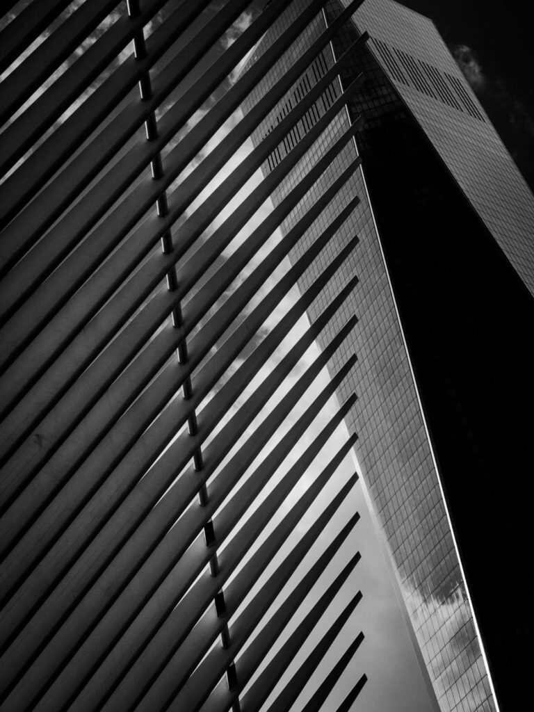 Black-and-white photo of a modern building with diagonal louvers running along the left side and a glass façade on the right.